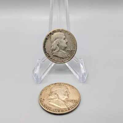 Sale Photo Thumbnail #15: Two US silver Franklin half dollars, dated 1954 and 1952, displayed on a clear plastic easel.
