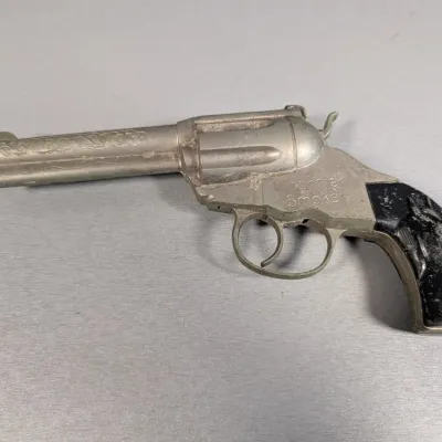 Sale Photo Thumbnail #314: Vintage Hubley Frontier Smoker die-cast metal toy cap gun featuring scrollwork detailing on the barrel and black horse-head grips.