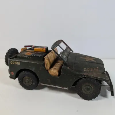 Sale Photo Thumbnail #51: Vintage tin litho military patrol jeep toy, featuring olive drab paint, star graphic, and rear equipment details with visible play wear.