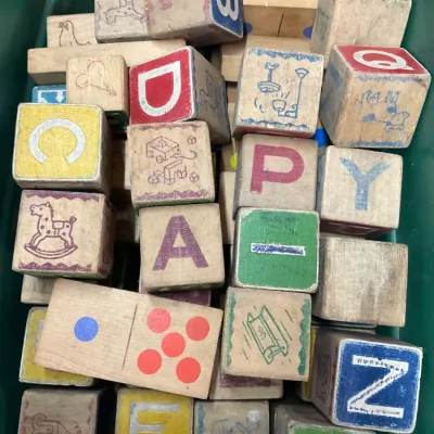 Sale Photo Thumbnail #256: Collection of vintage wooden alphabet building blocks and dominoes showing play wear, stored in a green plastic bin.