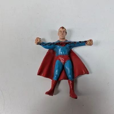 Sale Photo Thumbnail #416: Vintage painted lead Superman figurine depicting him breaking a chain, showing minor paint wear and age-appropriate patina.