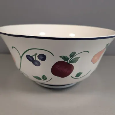Sale Photo Thumbnail #126: Pfaltzgraff 'Fruit Orchard' ceramic serving bowl featuring a white body with fruit motifs and a dark blue rim, in good condition.