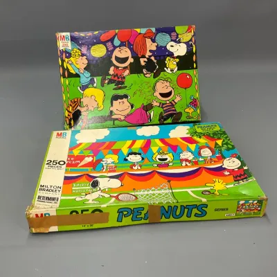 Sale Photo Thumbnail #108: Two vintage Milton Bradley Peanuts 250-piece jigsaw puzzles in original boxes, showing edge wear and tape repair on the lower box.