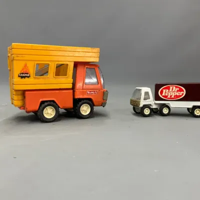 Sale Photo Thumbnail #291: Vintage pressed steel and plastic toy trucks, including an orange and yellow Buddy L camper truck and a smaller Dr. Pepper delivery truck.