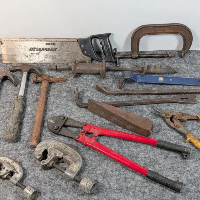 Sale Photo Thumbnail #91: Assortment of hand tools including hammers, pry bars, red bolt cutters, pipe cutters, tin snips, C-clamp, and a Sears backsaw.