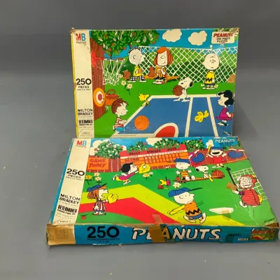 Sale Photo Thumbnail #107: Two vintage Milton Bradley Peanuts 250-piece jigsaw puzzle boxes, featuring sports scenes with Charlie Brown and Snoopy.