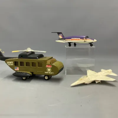 Sale Photo Thumbnail #300: Set of vintage toy aircraft including a Buddy L US Army helicopter, a Tonka Federal Express jet, and a white fighter jet model.
