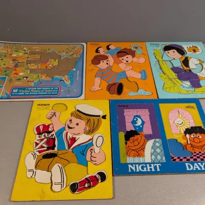 Sale Photo Thumbnail #445: Collection of vintage Playskool wood inlay puzzles, including a US map and Sesame Street scenes, showing moderate edge wear.