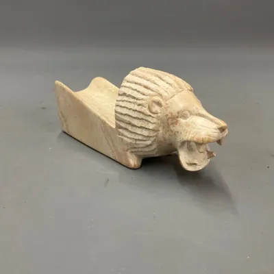 Sale Photo Thumbnail #246: Hand-carved stone lion-head pipe rest or decorative rest featuring an open-mouthed lion with a textured mane.