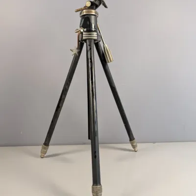 Sale Photo Thumbnail #446: Vintage mid-century camera tripod with black metal legs, adjustable pan handle, and star accent charm.