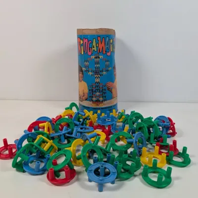 Sale Photo Thumbnail #53: Vintage Ringa-Majigs building set with a pile of colorful plastic ring pieces and the original cardboard storage container.