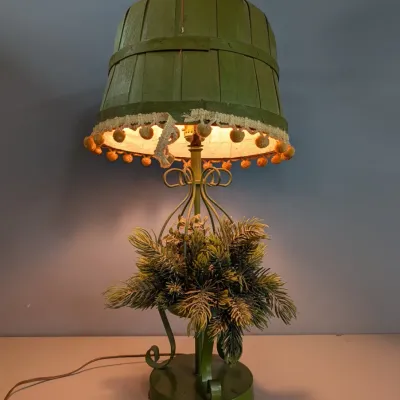 Sale Photo Thumbnail #328: Vintage green painted metal table lamp featuring a faux-evergreen planter base and an inverted wooden bushel basket lampshade trim with yellow pom-pom fringe.