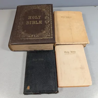 Sale Photo Thumbnail #450: Collection of four antique and vintage Bibles in varying sizes, bindings, and conditions, including a large brown cover edition with ornate gold tooling.