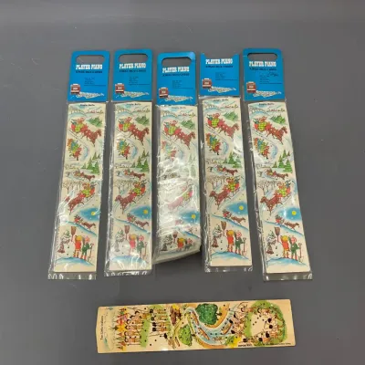 Sale Photo Thumbnail #404: Set of vintage Player Piano Xmas Musicards in original packaging featuring Christmas-themed illustrations, accompanied by an unpackaged paper music strip.