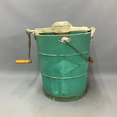 Sale Photo Thumbnail #263: Vintage hand-crank ice cream maker featuring a green wooden bucket, metal top gearing, and a yellow-handled crank handle.