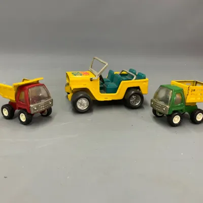 Sale Photo Thumbnail #289: Set of three vintage Tonka pressed steel toy vehicles, including two mini construction trucks and a yellow Jeep, showing minor play wear.