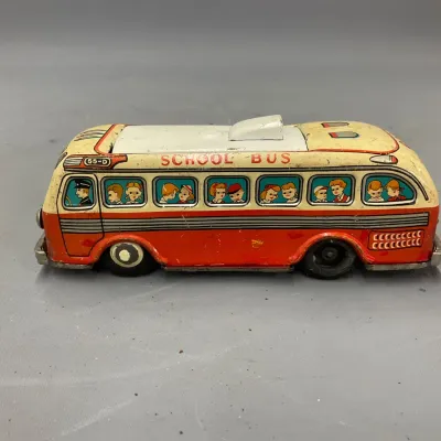 Sale Photo Thumbnail #281: Vintage lithographed tin school bus toy featuring red and cream paint with graphics of children in the windows.