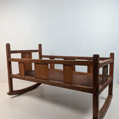 Sale Photo Thumbnail #58: Antique wooden doll or baby cradle with curved rocking runners and slatted side rails. Features faint floral decal accents on the end panels and shows a nicely aged patina throughout.