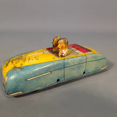 Sale Photo Thumbnail #413: Vintage lithographed tin convertible toy car featuring two passengers, displaying patina and play wear.