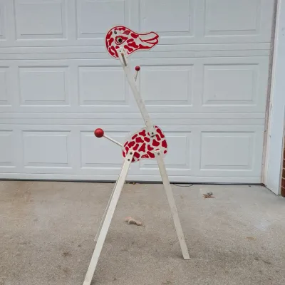 Sale Photo Thumbnail #60: Vintage mid-century wooden giraffe-shaped children's clothes rack featuring a red and white pattern and wooden pegs.