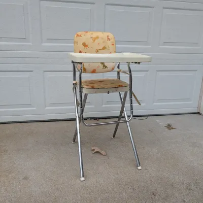 Sale Photo Thumbnail #62: Vintage folding high chair with chrome legs, a plastic tray, and animal-patterned vinyl upholstery.