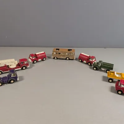 Sale Photo Thumbnail #357: Collection of vintage die-cast toy trucks and vehicles, including fire engines, a camper, and utility trucks showing play wear.