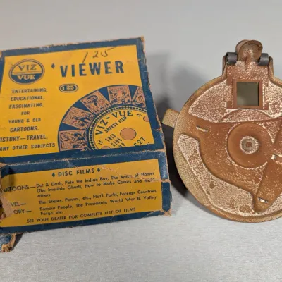 Sale Photo Thumbnail #324: Vintage Viz-Vue disc film viewer in brown metal finish with its original worn cardboard box, circa 1940s.