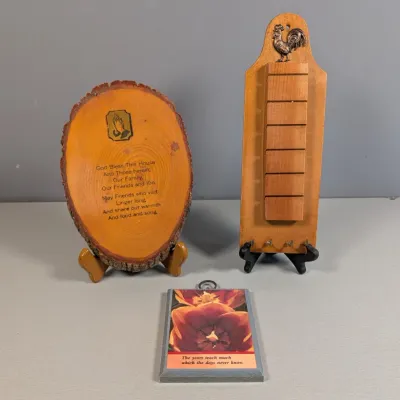 Sale Photo Thumbnail #323: Trio of vintage wooden wall decor items, including a live-edge log slice plaque with a religious blessing, a rooster-topped key rack, and a small floral quote plaque.
