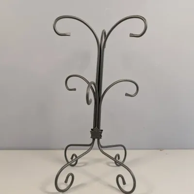 Sale Photo Thumbnail #124: Black wrought iron countertop mug tree or ornament display stand with scrolled hooks and a leaf accent at the base.