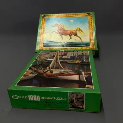 Sale Photo Thumbnail #229: Two vintage Whitman Guild 1000-piece jigsaw puzzles featuring horse and harbor scenes, showing mild edge wear on the original boxes.
