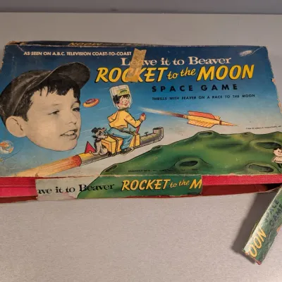 Sale Photo Thumbnail #305: Vintage 1959 Leave It to Beaver "Rocket to the Moon Space Game" by Hasbro, showing significant box wear and torn side flaps.
