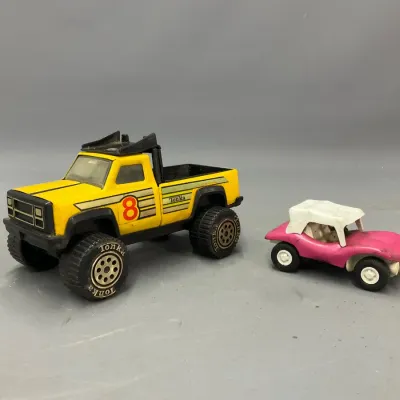 Sale Photo Thumbnail #290: Vintage Tonka yellow #8 pickup truck with oversized tires alongside a small pink beach buggy toy, showing light play wear.