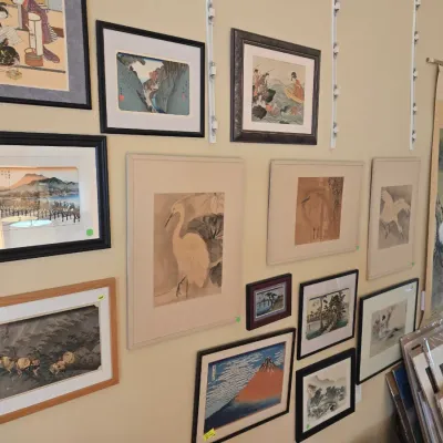 Sale Photo Thumbnail #34: Japanese ukiyo-e style woodblock prints and ink paintings featuring landscapes, birds, and traditional figures, paired with a hanging scroll.