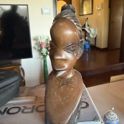 Hand-carved wooden bust sculpture depicting an African woman with stylized features and a topknot hairstyle.