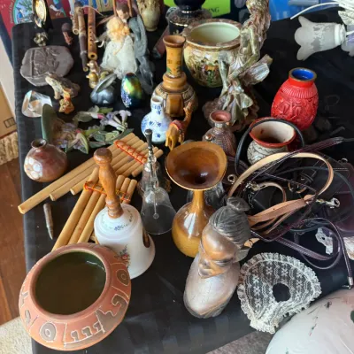 Assortment of eclectic collectibles and home decor including ceramic vases, a carved wooden bust, hand bells, pan flutes, figurines, and...