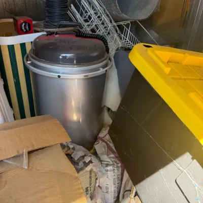 Assorted workshop and storage items including a cylindrical shop vacuum, rolls of wire fencing and mesh, a yellow-topped plastic storage...
