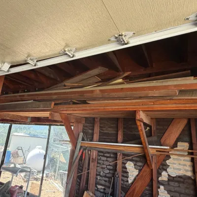Assorted lumber and wooden boards stored on overhead shelving in a garage workspace.