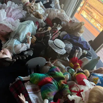 Large collection of vintage porcelain and collectible dolls dressed in various ornate costumes, displayed together.