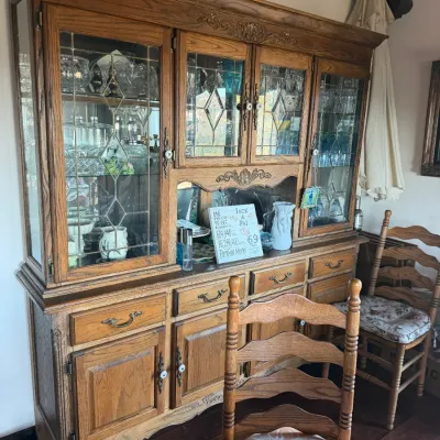 Large vintage oak china cabinet featuring leaded glass doors, carved accents, and lower storage drawers and cupboards.