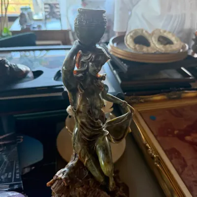 Carved soapstone or jadeite figure of a maiden holding a vessel atop her head, resting on a rocky base.