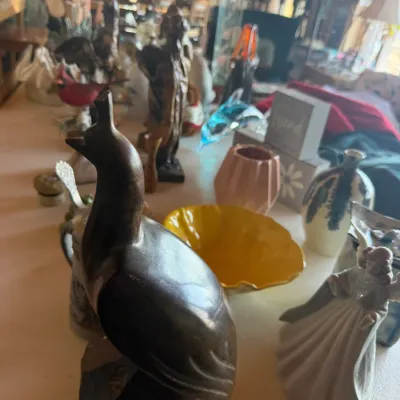 Collection of tabletop decor and collectibles including a carved stone bird sculpture, porcelain figurine, yellow art glass bowl, and...