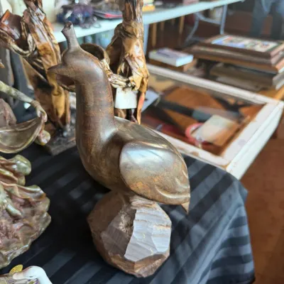 Hand-carved wooden bird figurine, featured alongside other collectible sculptures and folk art pieces.