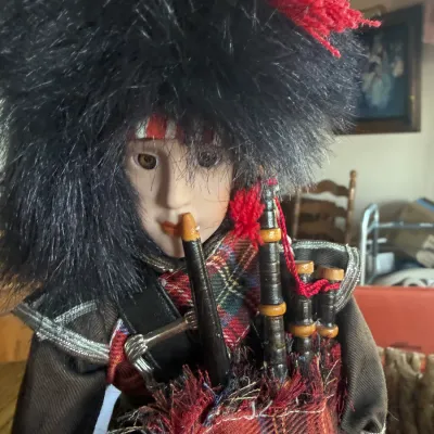 Vintage Scottish bagpiper doll wearing traditional tartan attire and a faux fur bearskin hat.