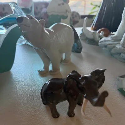 Vintage ceramic animal figurines, featuring a glazed white polar bear and a dark brown elephant with white tusks.
