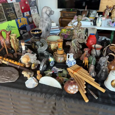 Eclectic assortment of tabletop decor, including wooden flutes, pan flutes, ceramic vases, glass bells, and various animal figurines...