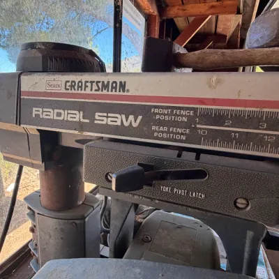 Vintage Sears Craftsman radial arm saw showing original branding, yoke pivot latch, and fence positioning measurements. The tool displays...
