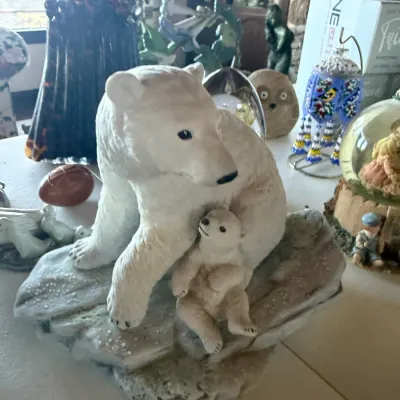 Realistic porcelain figurine depicting a polar bear mother and her cub resting on a snowy rocky base.