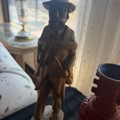 Hand-carved wooden figurine of a bearded man with a hat, poncho, and walking stick.