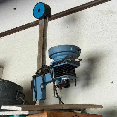 Vintage blue photographic darkroom enlarger with adjustable bellows mounted on a vertical column.