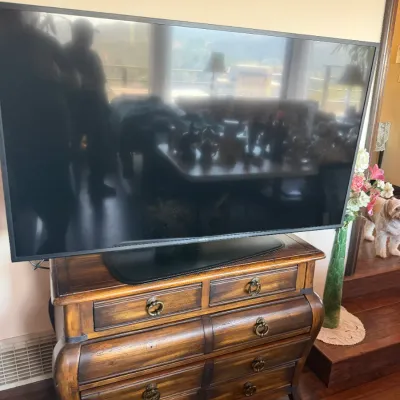 Large flat-screen Sony television resting on a rustic wooden bombona-style chest with brass hardware.